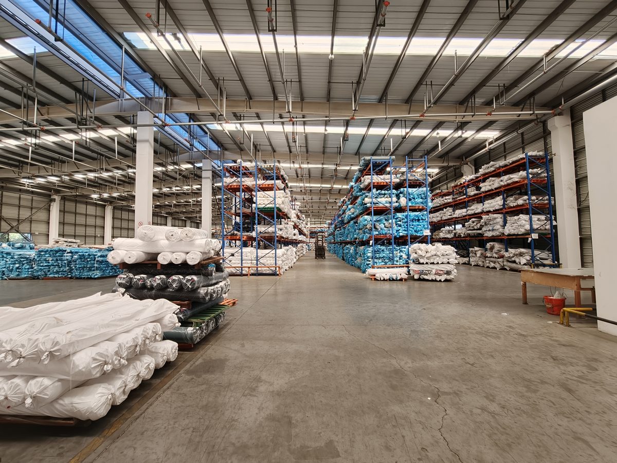 Finished fabric warehouse with packed rolls on high racks ready for export