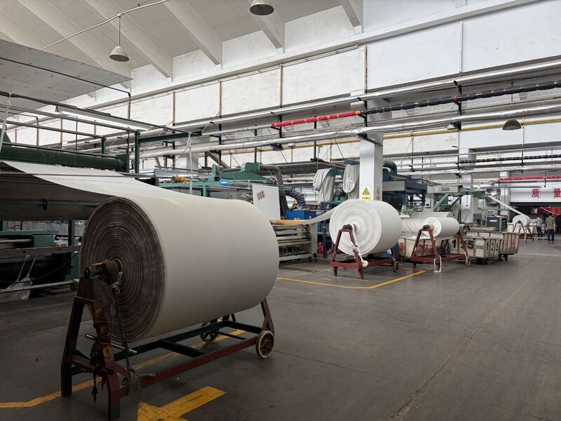 Large fabric batch rolls on A-frames in the finishing hall